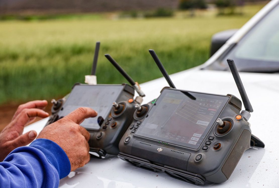Agricultores usam controles de drone para monitorar uma propriedade rural e apoiar decisões de agricultura de precisão.