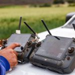 Agricultores usam controles de drone para monitorar uma propriedade rural e apoiar decisões de agricultura de precisão.