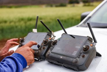 Agricultores usam controles de drone para monitorar uma propriedade rural e apoiar decisões de agricultura de precisão.