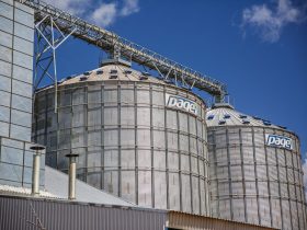 Silos industriais de grãos em Paragominas, no Pará, sob céu azul.